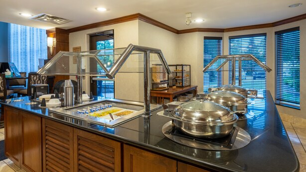 Ein Buffetbereich mit Glastrennwand, Edelstahl-Buffetschalen und einer Kaffeestation.