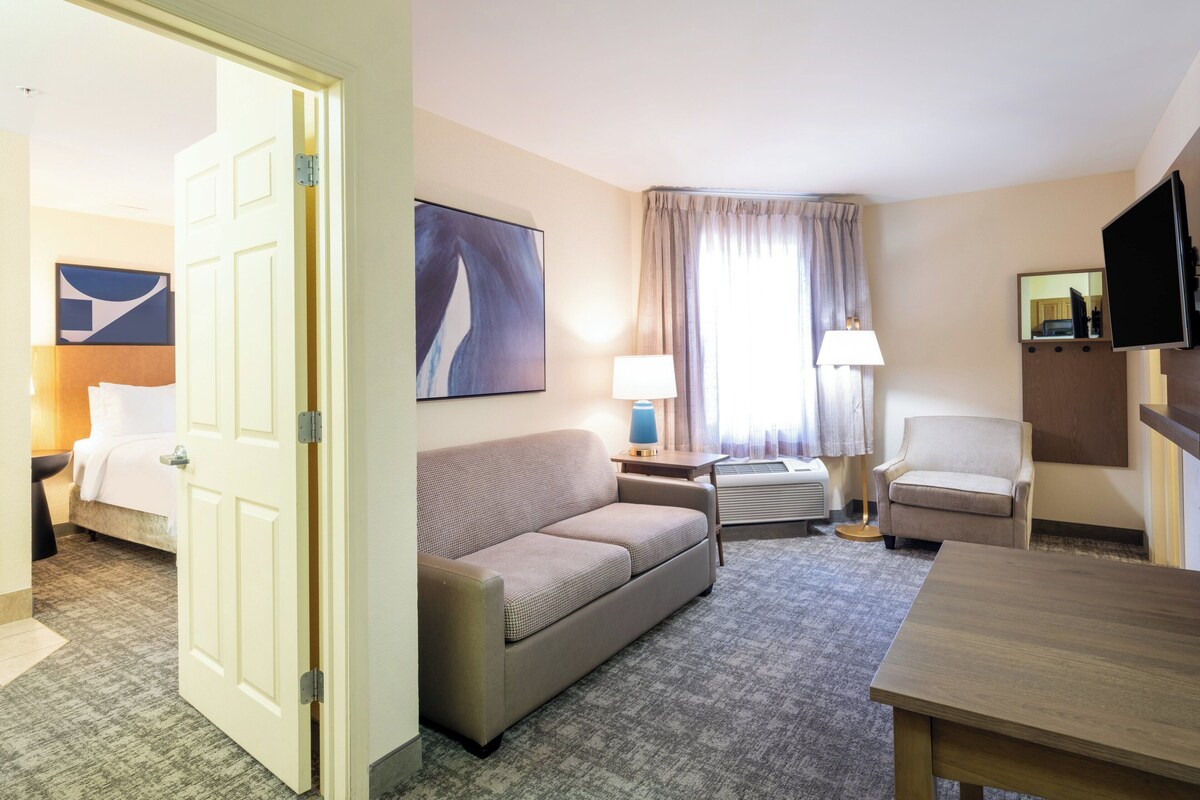 Ein Hotelzimmer mit einem Bett, einem Sofa, einem Schreibtisch, einem Stuhl und einem Fernseher.
