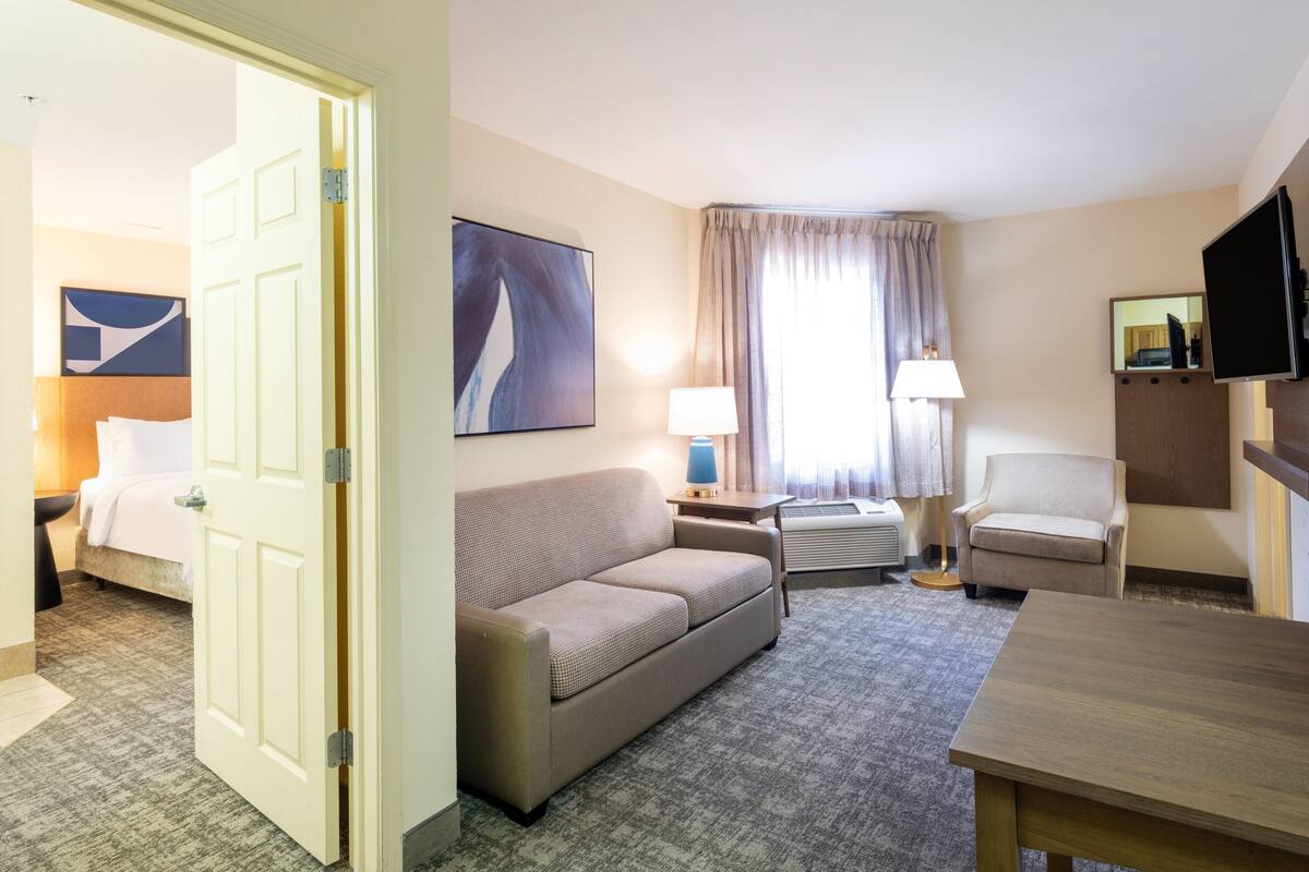 Une chambre d’hôtel avec un lit, un canapé, un bureau, une chaise et un téléviseur.