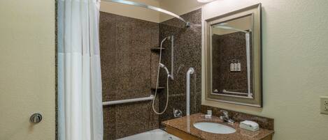 Un baño con bañera, ducha, lavamanos y espejo.