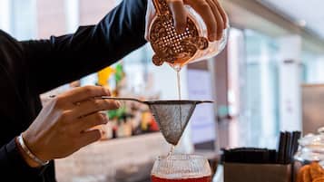 Een barman giet een drankje in een martini-glas.