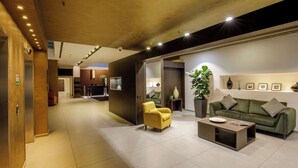 A modern hotel lobby with a yellow armchair, a green sofa, and a coffee table. - DoubleTree by Hilton Milan (Milan)