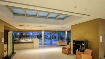 A lobby with a reception desk, seating area, and a view of the street outside.