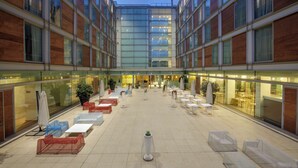 A spacious outdoor area with multiple seating arrangements and a central plant. - DoubleTree by Hilton Milan (Milan)