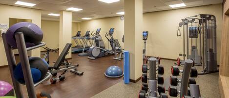 A gym with treadmills, elliptical machines, free weights, and exercise balls.