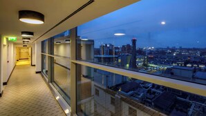 A corridor with glass walls and a city view at dusk. - DoubleTree by Hilton Milan (Milan)