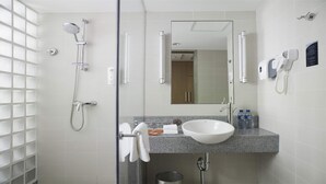 Un baño moderno con cabina de ducha de vidrio, un lavabo blanco y un espejo sobre el lavabo.