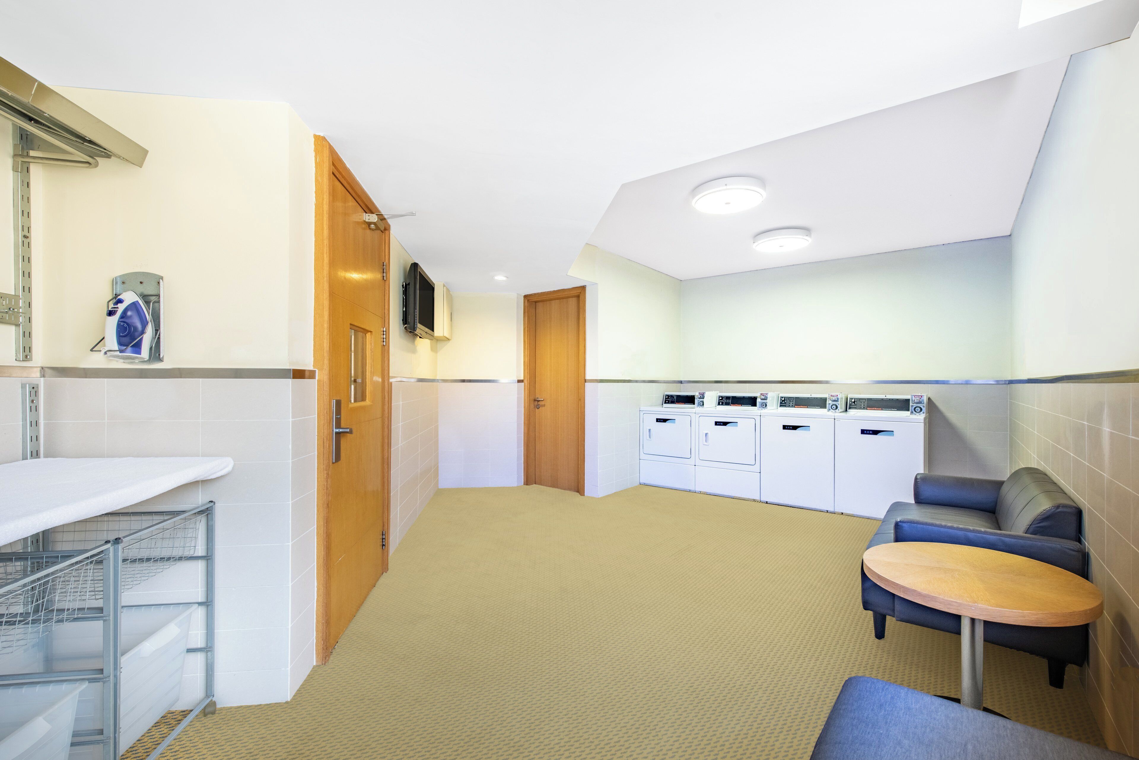 A clean, modern laundry room with a washing machine, dryer, and ironing station.