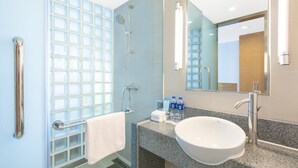 Un baño moderno con cabina de ducha de vidrio, un lavabo blanco y un perchero para toallas.