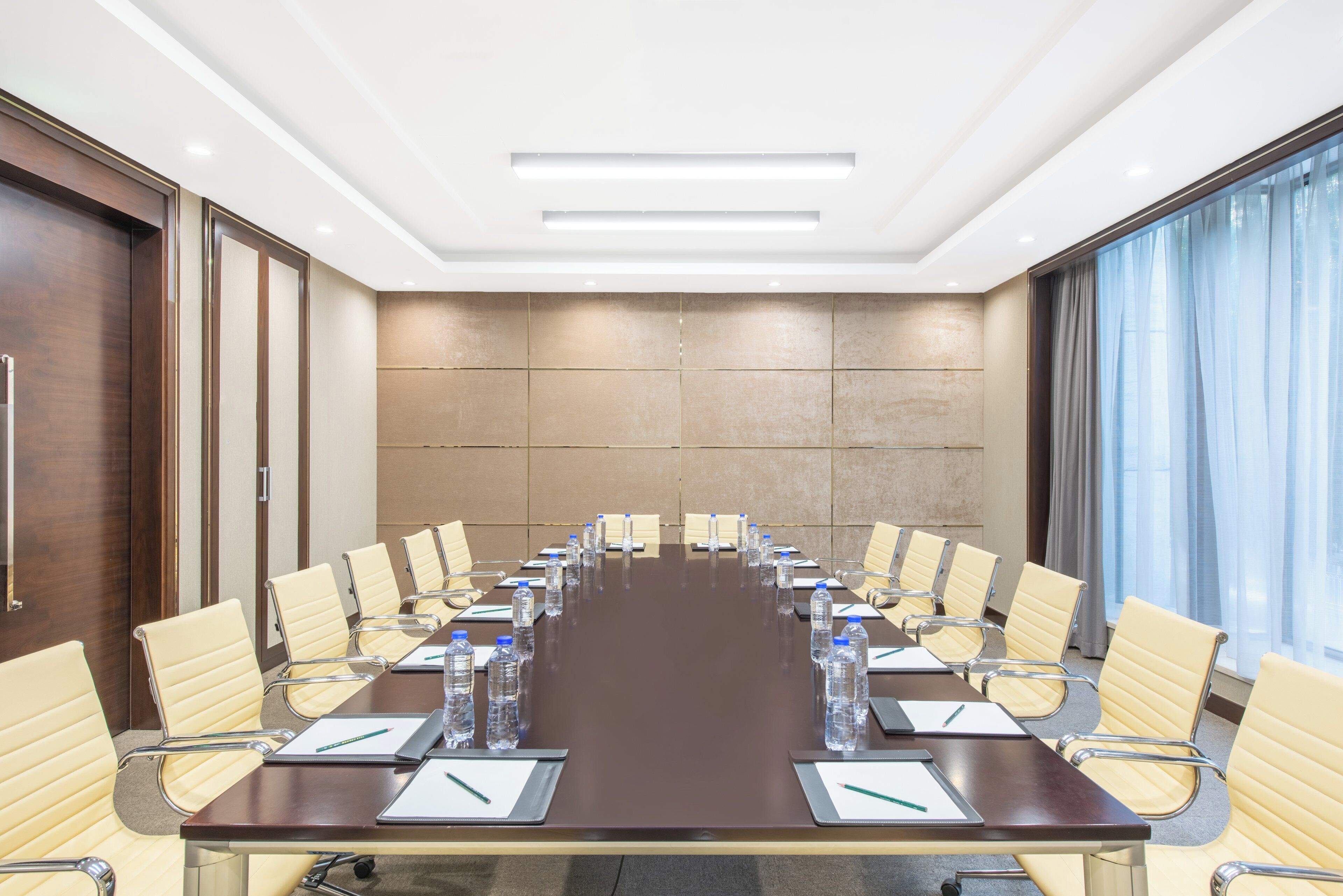 A conference room with a long table, chairs, water bottles, and notepads.