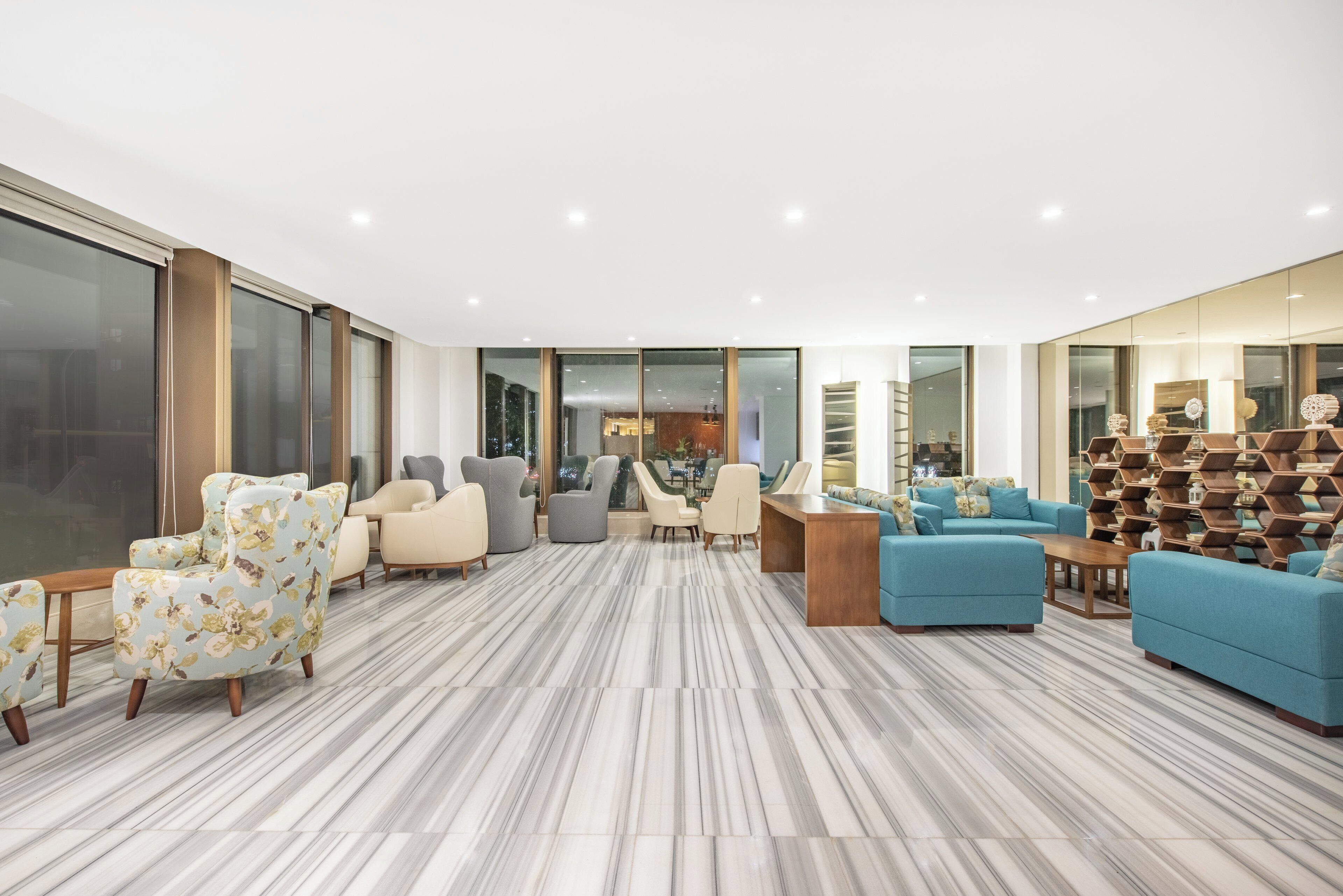 A spacious living area with a large window, a seating arrangement, and a decorative wall.