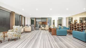 A spacious living area with a large window, a seating arrangement, and a decorative wall.