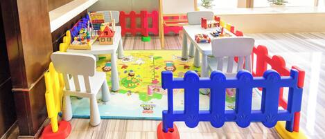 A children's play area with tables, chairs, and a play mat.