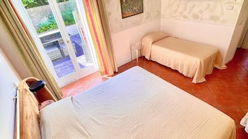 Ein Hotelzimmer mit einem großen Bett, einem an der Wand befestigten Fernseher und einer Schiebetür zu einem Balkon.