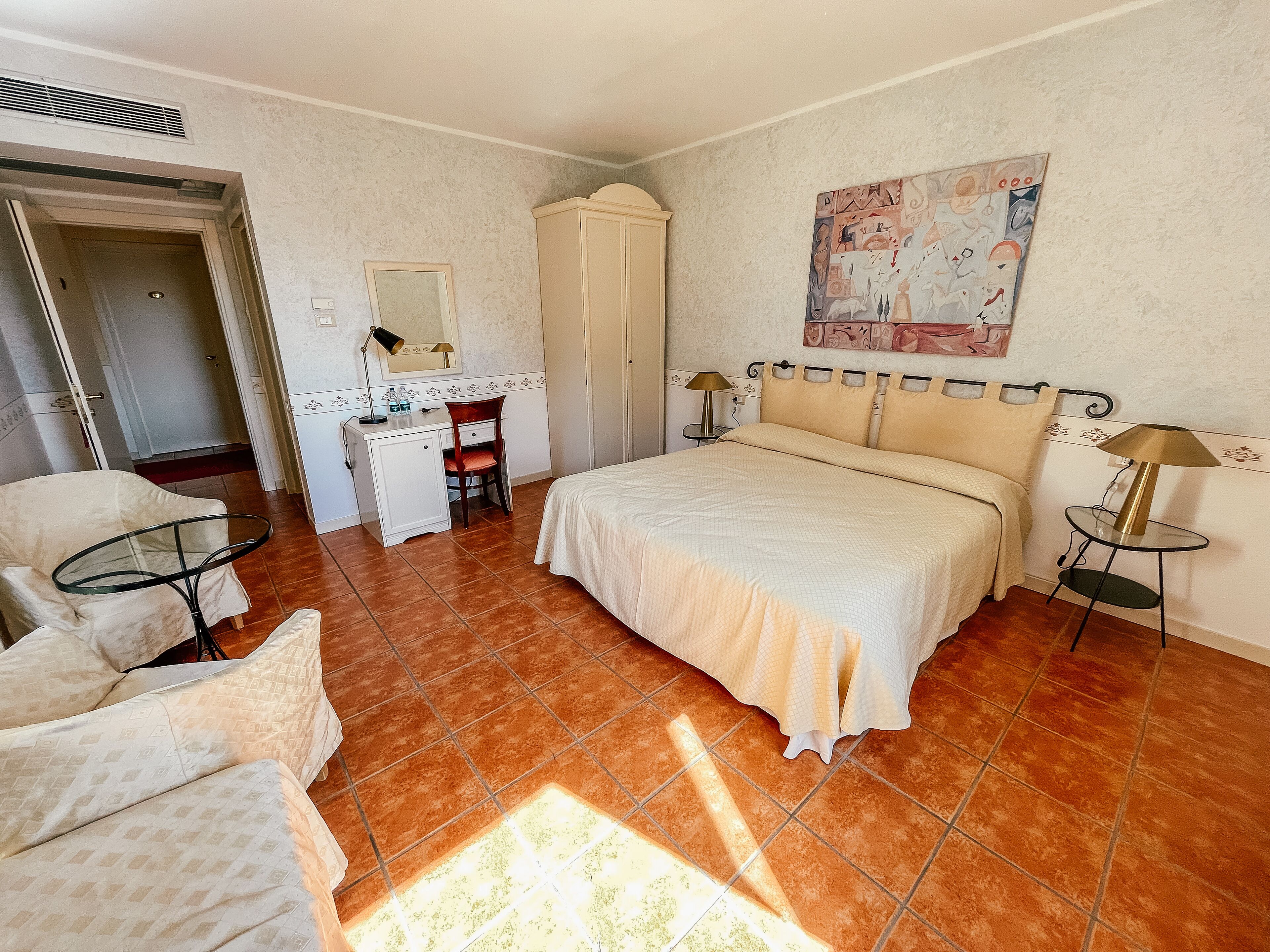 Un dormitorio con cama, escritorio, silla, armario y un cuadro en la pared.