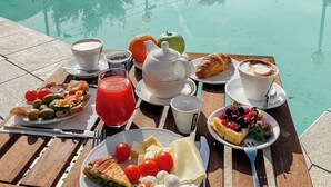 A dining table with breakfast items by a poolside. - Hotel Caroline (Brusimpiano)