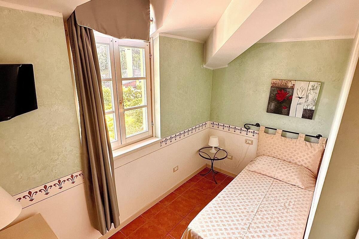 A bedroom with a bed, a window, a TV, and a small table.