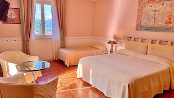 Habitación de hotel con dos camas, una mesita, una silla y una ventana con cortinas.