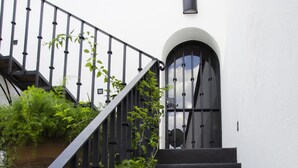 Una escalera con escalones negros que conduce a una puerta con un ventanal circular.