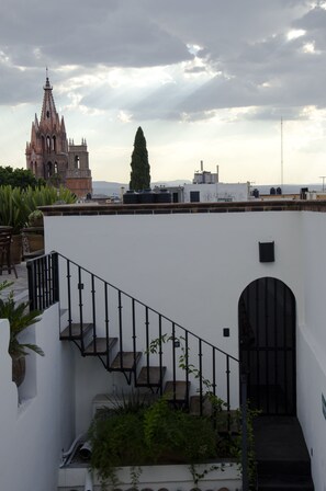 A rooftop terrace with a staircase, potted plants, and a view of a historic church.