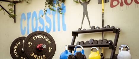 A gym with weightlifting equipment, including dumbbells and a barbell, and a wall with motivational words and a silhouette of a person lifting weights.