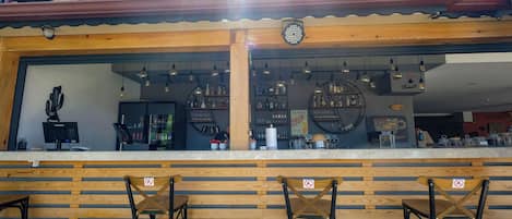 Un espace bar avec des lambris en bois, un comptoir et trois chaises.