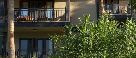 A two-story building with balconies, surrounded by lush greenery and palm trees.