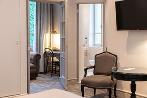 Habitación de hotel con cama, escritorio con silla, mesa redonda y televisor montado en la pared.