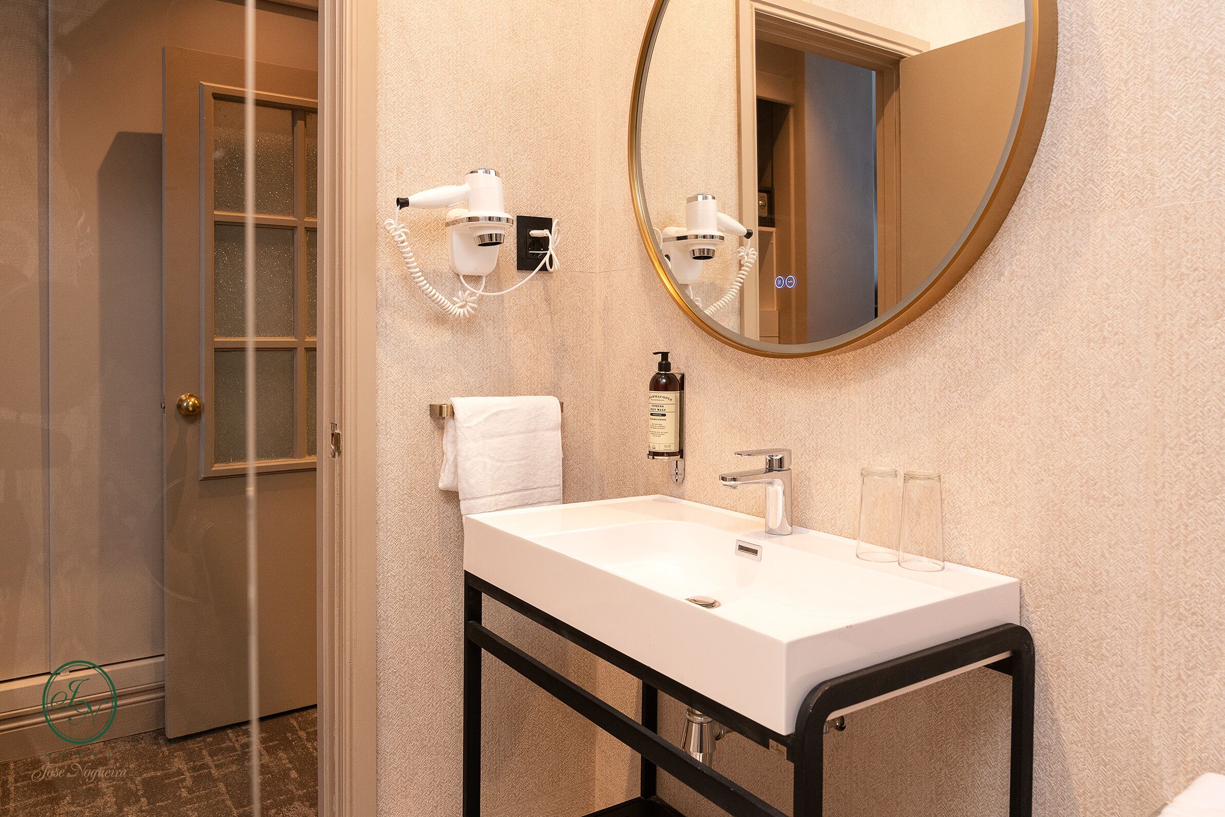 A bathroom with a white sink, a mirror, a hairdryer, and a towel.