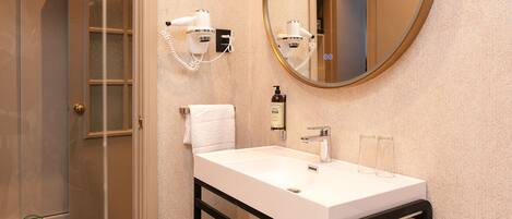 A bathroom with a white sink, a mirror, a hairdryer, and a towel.