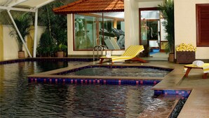 Ein Innenpool mit gefliestem Deck, Fitnessgeräten und Liegestühlen.