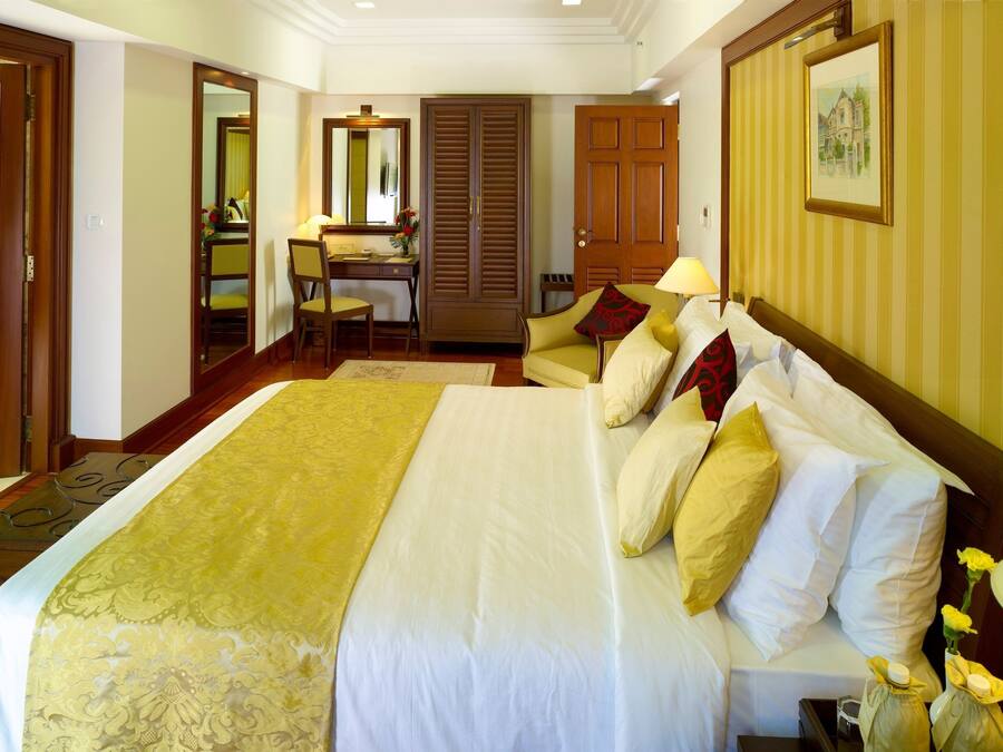 A hotel room with a large bed, a desk, and a chair.
