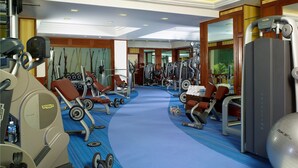 Ein Fitnessstudio mit Cardiogeräten, Gewichte und einer blauen Trainingsmatte.