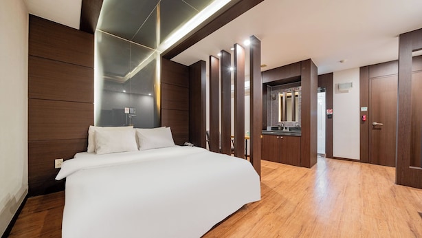 Une chambre d’hôtel moderne dotée d’un grand lit, de murs recouverts de panneaux en bois et d’une salle de bain séparée.