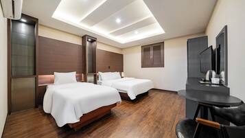 A hotel room with two beds, a desk, and a mirror.