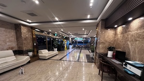 Un hall d’hôtel comprenant un comptoir d’accueil, un espace salon et une vue sur la salle à manger.