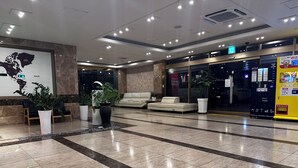 Un hall d’entrée moderne avec un espace salon, des plantes en pot, une carte accrochée au mur et un distributeur automatique.