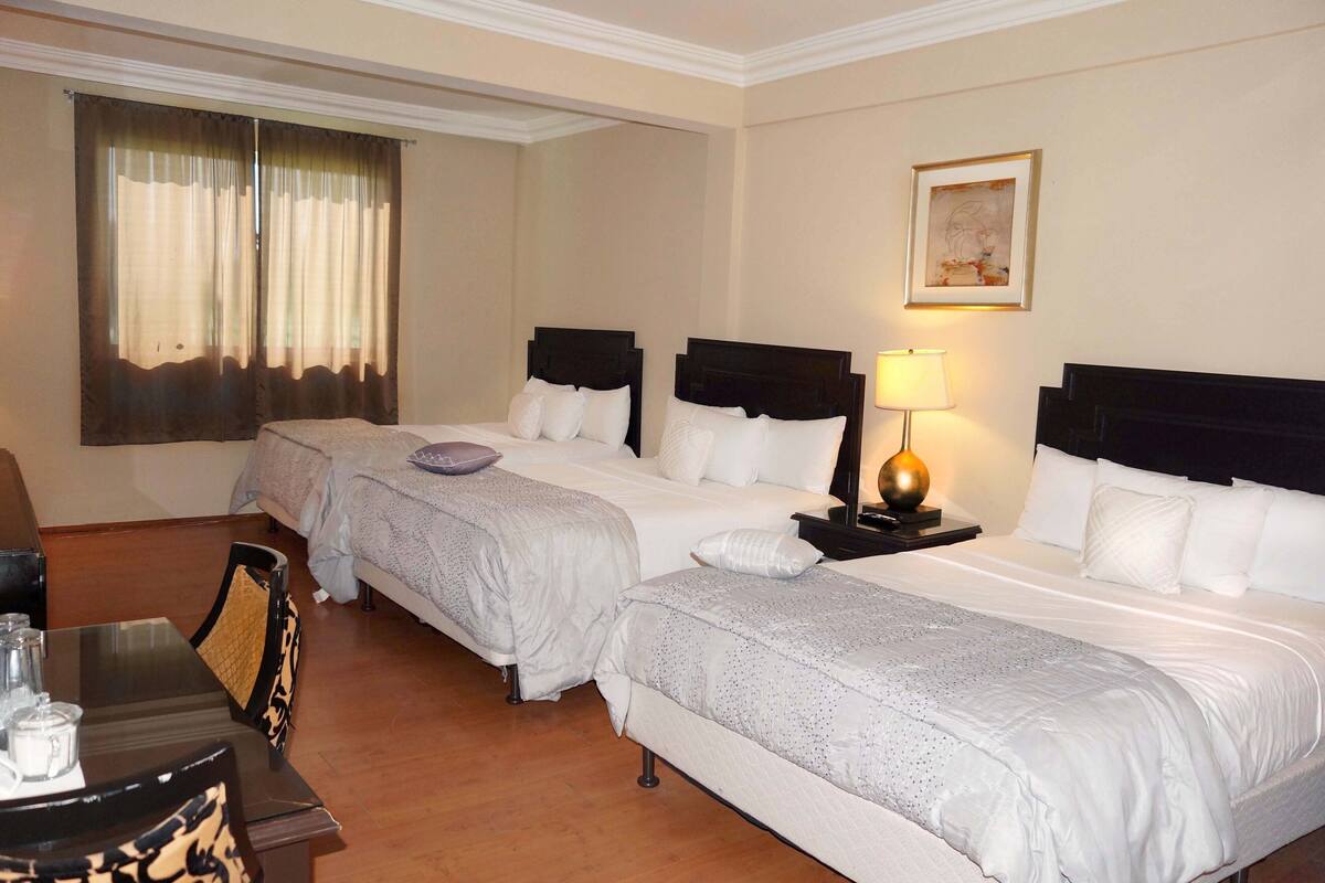 Een hotelkamer met twee bedden, een bureau met stoel, een lamp en een schilderij aan de muur.