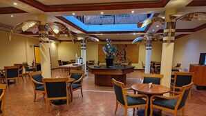 Een hotel lobby met houten meubels, een centraal gelegen receptiebalie en een dakraam.