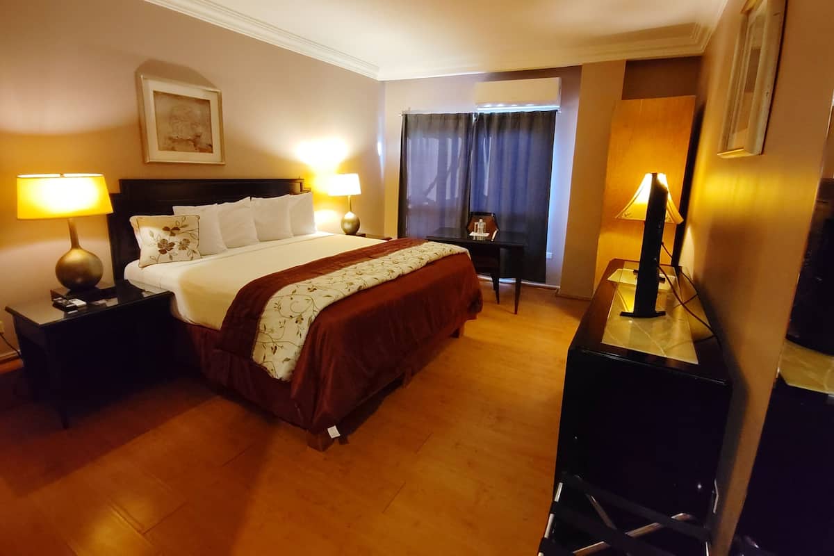 Een hotelkamer met een groot bed, twee bedlampen, een bureau en een televisie.