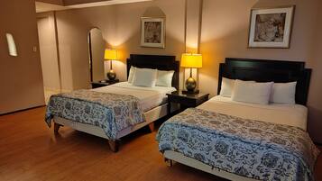 Une chambre d’hôtel avec deux lits, chacun doté d’une tête de lit, de tables de chevet, de lampes et d’une couvre-lit à motifs floraux.