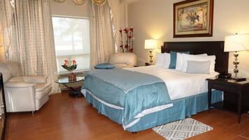 A hotel room with a bed, a chair, a nightstand, a lamp, and a painting on the wall.