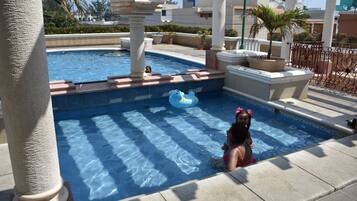 Guests can enjoy a refreshing swim in the pool surrounded by lush greenery and architectural details.