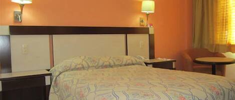 A hotel room with a large bed, two bedside tables, a chair, and a small table.