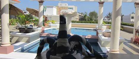 A pool area with a person relaxing on a lounge chair.