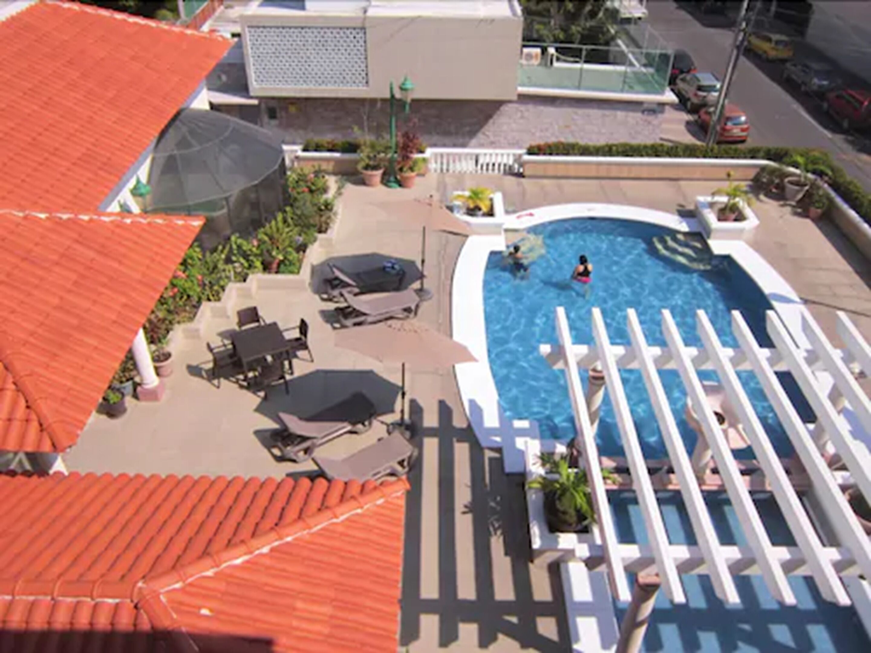 A rooftop pool area with lounge chairs, a swimming pool, and a covered seating area.