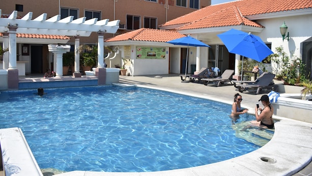 A swimming pool with a pergola, lounge chairs, and umbrellas.
