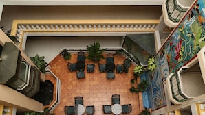 An outdoor seating area with tables and chairs, surrounded by potted plants and a decorative wall.