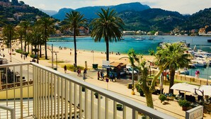 Una passejada marítima amb palmeres, una platja i vaixells al fons.