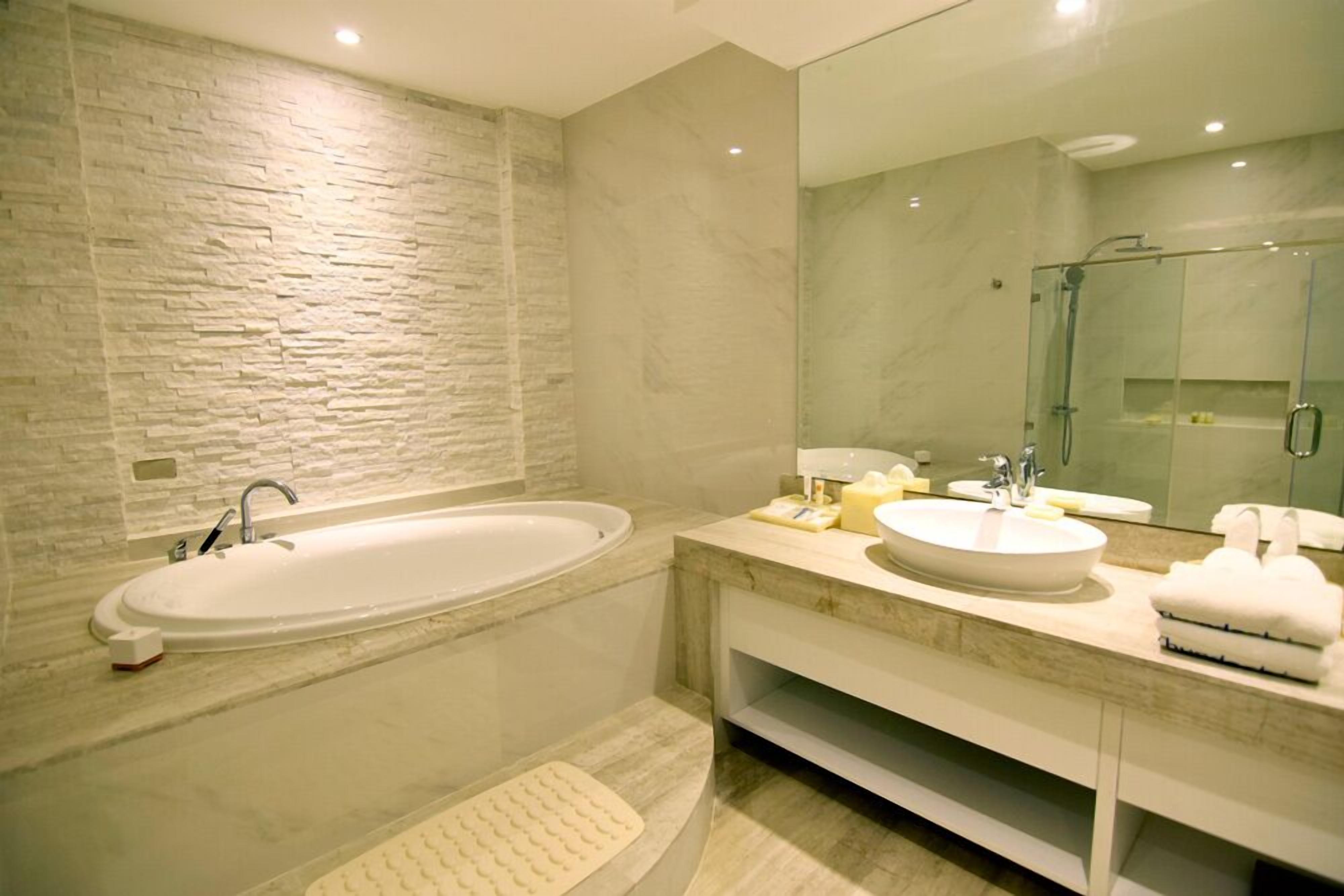 Un baño moderno con una bañera independiente grande, dos lavamanos y una ducha con cerramiento de vidrio.